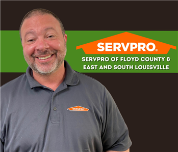 man smiling at camera with a black background and a SERVPRO logo with Floyd County and East & South Louisville written under